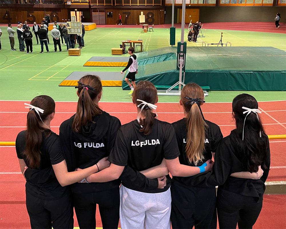 Mehrere Sportlerinnen der LG Fulda blicken Arm in Arm richtung Wettkampffläche